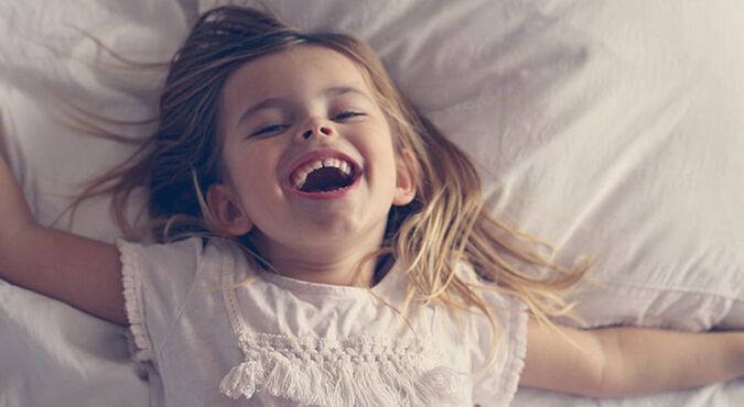 Niña feliz acostada en la cama